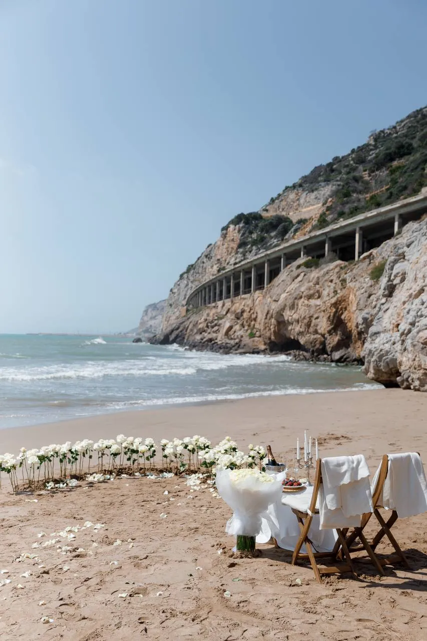 Ginesta beach marriage proposal setup with white roses and cliffs 1