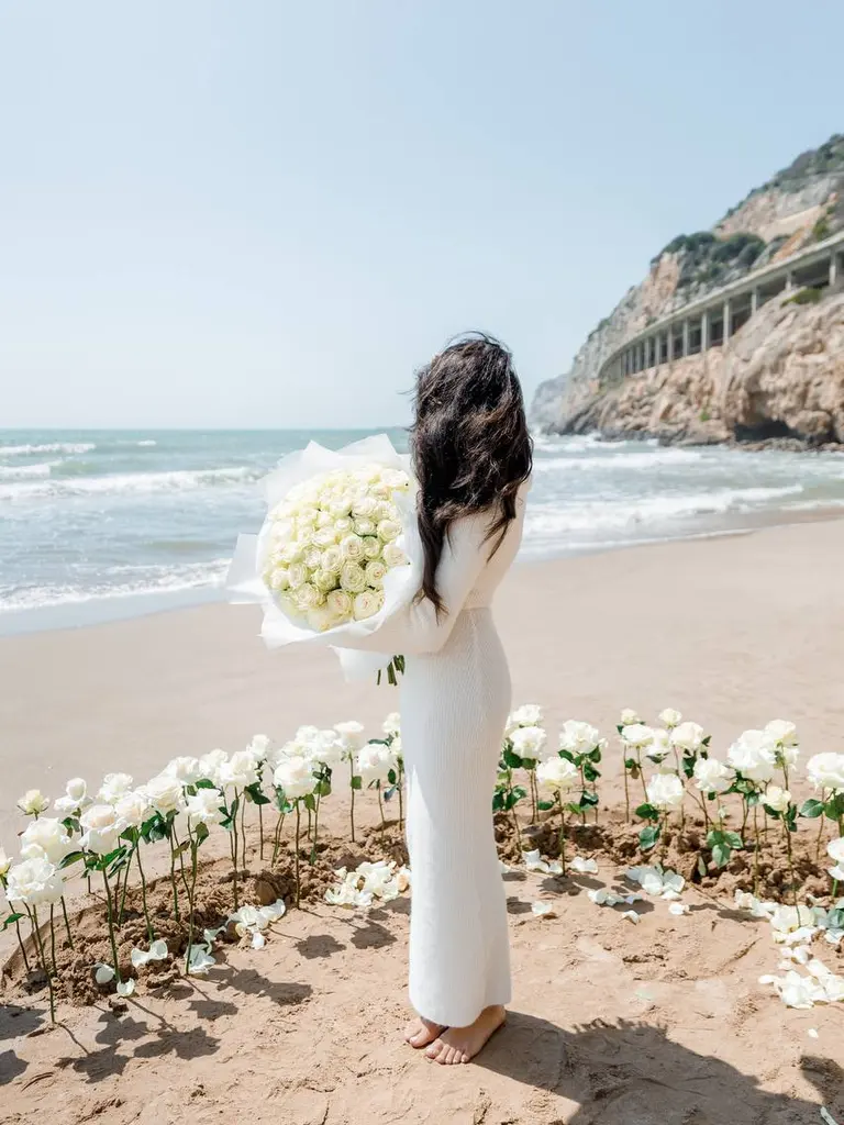 Ginesta beach marriage proposal setup with white roses and cliffs 3
