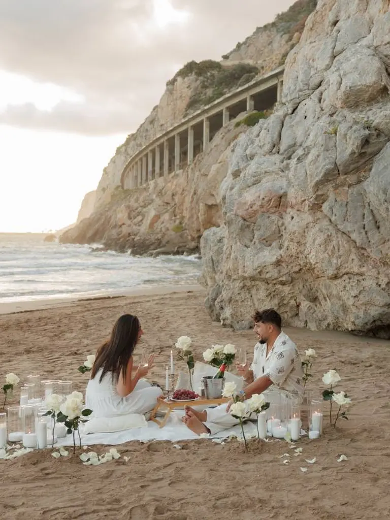 Ginesta beach marriage proposal setup with white roses and cliffs 4